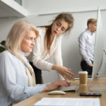 Young team leader correcting offended senior employee scolding