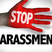 Stop Harassment text written on hand and background
