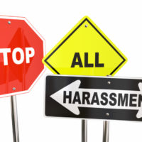 Three signs that read stop all harassment