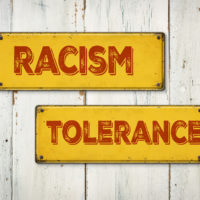 Racism and tolerance Direction signs on a wooden wall Racism and tolerance Direction signs on a wooden wall