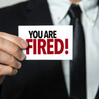 You Are Fired written on notecard held by businessman