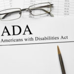 Notepad that reads Americans with Disabilities Act (ADA) on a table with spectacles and pen