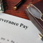 Severance Pay doc, glasses, planner and pen on table Severance Pay doc, glasses, planner and pen on table
