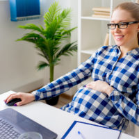 Tired pregnant woman working in office