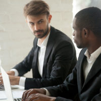 Caucasian businessman looking at african business rival