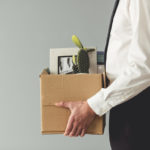 Businessman getting fired holding a box with stuff