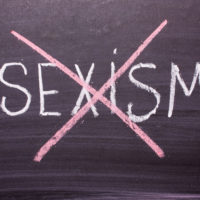 Stop sexism is written on a chalkboard crossed out