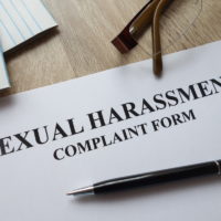 Sexual harassment complaint form with pen, calculator and glasses on desk Sexual harassment complaint form with pen, calculator and glasses on desk