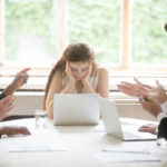 Male colleagues pointing fingers at upset female boss on meeting