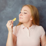 Cute young woman enjoy eating potato chips