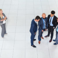 Men talking in a group excluding woman employee as part of sex discrimination Men talking in a group excluding woman employee as part of sex discrimination