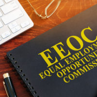 Book that reads eeoc on desk with pen and keyboard