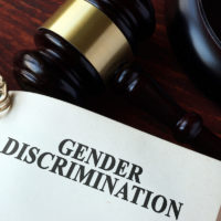 Book with chapter gender discrimination and a gavel. Book with chapter gender discrimination and a gavel.