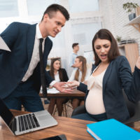 3335656 Angry young man in suit screams at pregnant girl in office. Pregnancy at work.