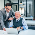 Young man working with boss or older employee in the office.