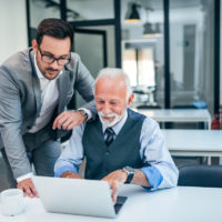 Young man working with boss or older employee in the office.