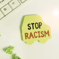 Handwriting text writing Stop Racism. Concept meaning end the antagonism directed against someone of a different race Green note paper in the shape of the car. Copy space on the green note paper.