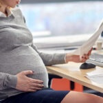 pregnant businesswoman reading papers at office