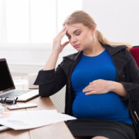 Tired pregnant businesswoman at office copy space