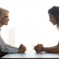 Young and old businesswomen sitting opposite, generations conflict at work