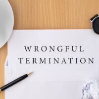 Wrongful termination document on wooden table with pen and smartwatch, termination of employment and resignation concept