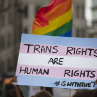 A person holding a pro transgender banner at a gay pride event