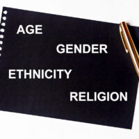 AGE GENDER ETHNICITY RELIGION words in white letters on black paper with golden pen. Equality diversity concept. Census concept