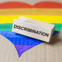 Discrimination word on wooden block on lgbtq flag in heart