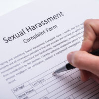 Human Hand Filling Sexual Harassment Complaint Form