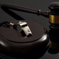 Whistleblower protection law and freedom of information legislation conceptual idea with metal whistle and wooden judge gavel on dark background