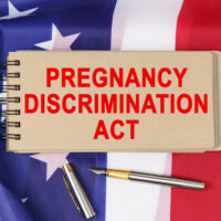 Against the background of the flag of the USA lies a notebook with the inscription - PREGNANCY DISCRIMINATION ACT