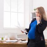 Pregnant business woman talking on phone at office