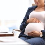 Young pregnant woman in suit at workplace, closeup. Space for text