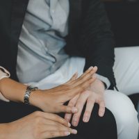 Unhappy asian young employee woman defending at hand of colleagues, man or boss touching her knee feeling disgusted and uncomfortable. Sexual harassment inappropriate at office, workplace concept. Unhappy asian young employee woman defending at hand of colleagues, man or boss touching her knee feeling disgusted and uncomfortable. Sexual harassment inappropriate at office, workplace concept.