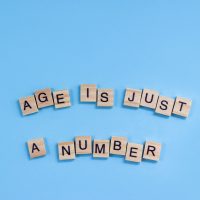 Phrase Age is just a number. Wooden blocks with lettering on a blue background. Ageism concept.