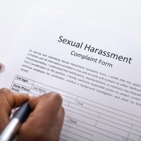 Human Hand Filling Sexual Harassment Complaint Form With Pen