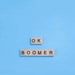 The phrase ok boomer. Wooden blocks with letters on a blue background. Age discrimination concept. Copy space