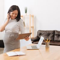 Joyful pregnant woman working in the office