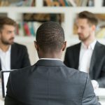 Rear view at african businessman sitting against two caucasian m