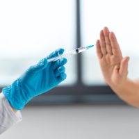 nurse with syringe and woman refusing from vaccine