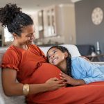 Happy lovely daughter hugging pregnant mother