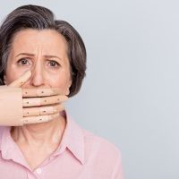 Photo of unhappy upset old woman hand cover close mouth silence empty space isolated on grey color background