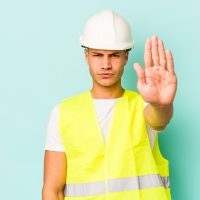 standing with outstretched hand showing stop sign, preventing you. standing with outstretched hand showing stop sign, preventing you.