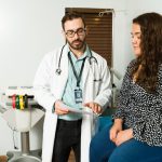 Cardiologist specialist reading the lab results and giving a prescription to a female patient at the office