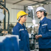 Male foreman flirting talking with female colleague worker dissatisfied and boring, sexual harassment situation bully in workplace