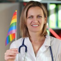 Smiling female doctor with lgbt flag in her hand in clinic office.