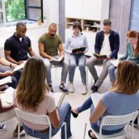 Diverse Group Reading And Studying Bible. People In Circle