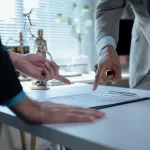 Legal professionals examining contract provisions, law office setting featuring gavel and Themis statuette