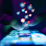 Finger of woman touching scroll page app on mobile phone.In a room with blue and purple neon tones.concept Social Media, Marketing, Post - Structure, Image-based Social Media, like buttons